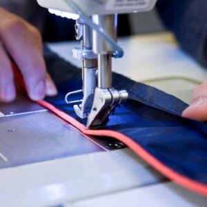 A steady hand; the lifejacket outer cover is carefully stitched.